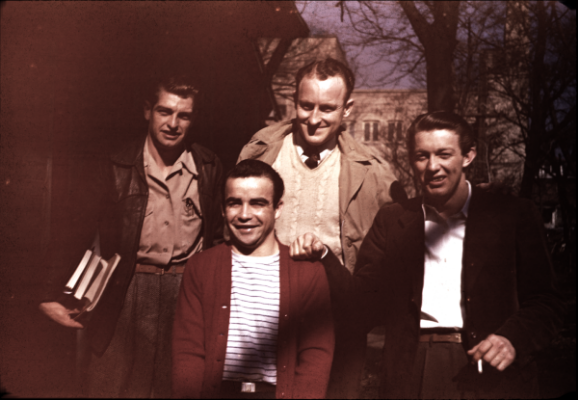 Four young male students pose for a photo with their books