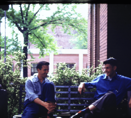 Two students are sitting on a porch on campus