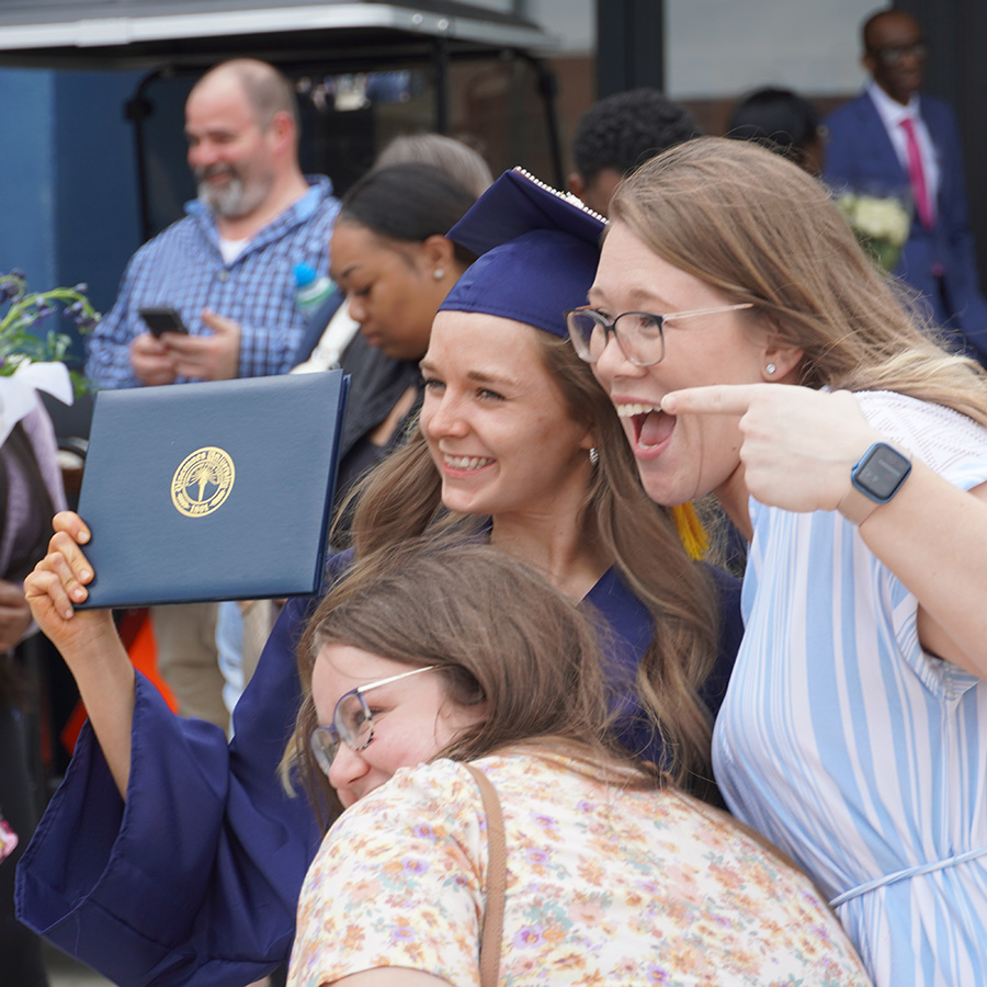 student posing for picture with parents at graduation