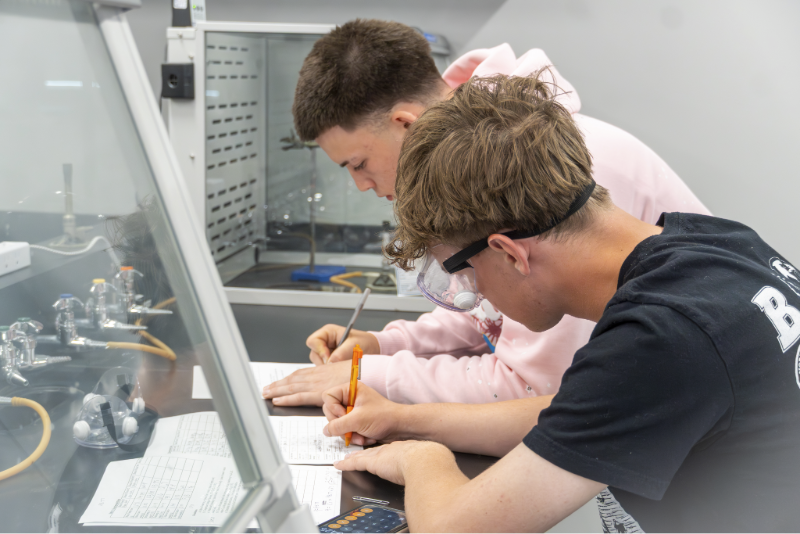 Two young students in a lab work intently on paperwork.