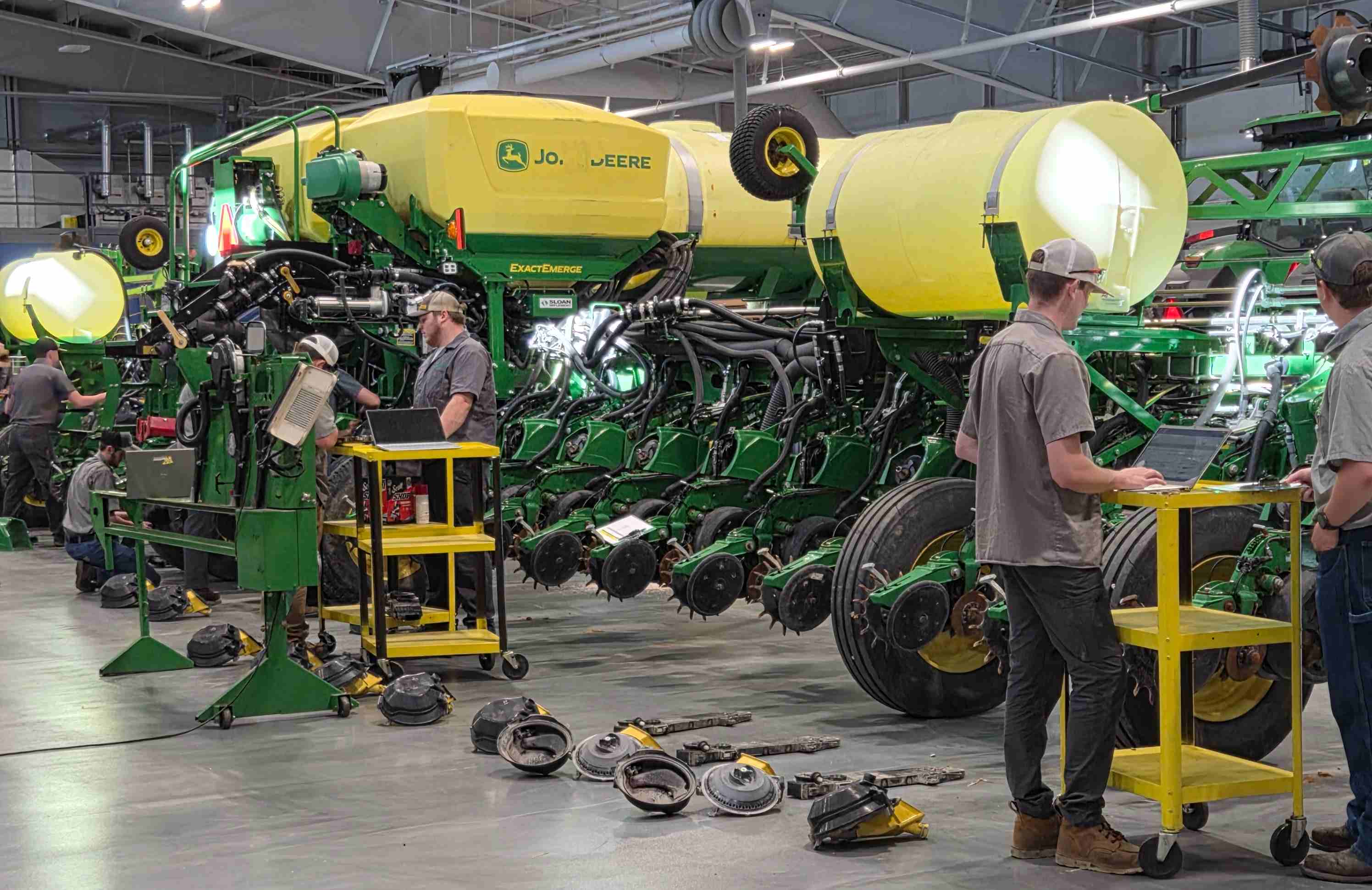 Male college students using laptops to work on a large John Deere planter inside a spacious lab at the VU Ag Center.